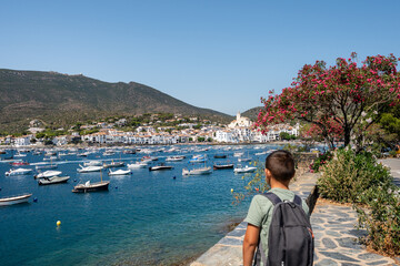 Student walking near the port of cadaques, admiring the white houses and the moored boats, on a...