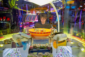 Teenage boy having fun at entertainment games arcade playing amusement center machines