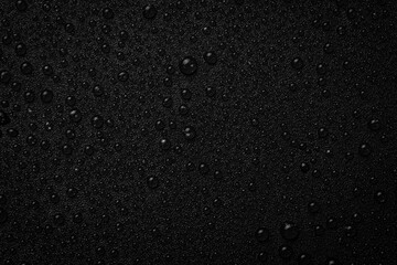 Water drops on a black background. Textured surface for design or text. Top view. Free space.