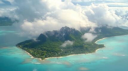 aerial view of a lush green tropical island surrounded by turquoise water with rocky hills partially covered by clouds under a blue sky