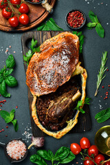 Baked turkey thigh with tomatoes, bell pepper. Traditional Turkish dish. On a black stone background.