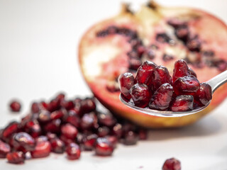 Remove seeds from a pomegranate with a spoon, cut in half, close-up of a ripe fruit