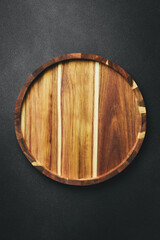 Kitchen wooden tray or board on a dark stone background. Top view. Free space for text.