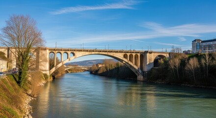 Naklejka premium Stone arch bridge spanning a river under a clear sky