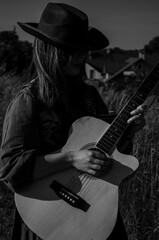 A girl with a guitar in cowboy style. Cowboy hat and boots. Sunny atmospheric photos.