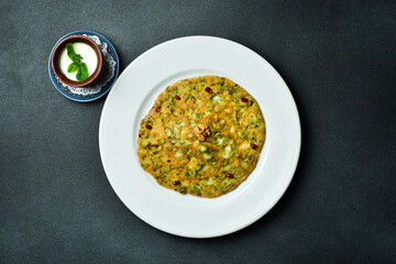 traditional Azerbaijan pancake with greens and salty yogurt. Free space for text. On a dark background.