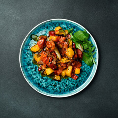 Stewed veal with pumpkin and vegetables on a plate. Close up. On a dark background.