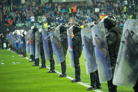 Security guards armed with shields on the football pitch during a soccer match