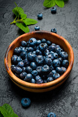 Close-up of blueberries in a bowl on a black slate table.