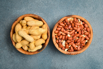 Two wooden bowls with peeled peanuts and peanuts in the shell. Nuts close-up.