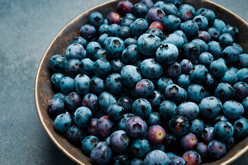 Fresh blueberries in a ceramic bowl. Close-up, free space for text.