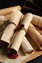 Many old rolled scrolls on black wooden table, closeup