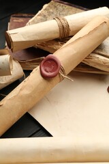 Many old rolled scrolls on black wooden table, closeup