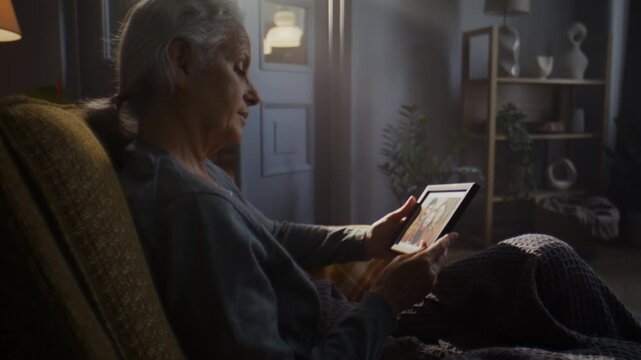 Senior woman looks at old photo frame remembering family at home