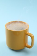 Aromatic coffee in cup on light blue background, closeup