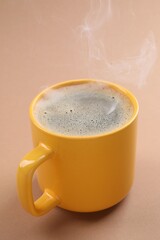 Aromatic coffee in cup on beige background, closeup
