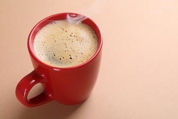 Aromatic coffee in cup on beige background, closeup. Space for text