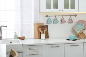 Different dishware on countertop and cups in kitchen