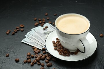 Cup of aromatic coffee, dollar banknotes and roasted beans on dark textured table, closeup