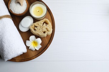Spa products, aromatherapy, atmosphere of relax. Spa essentials on wooden tray in bathroom, essential oil, bath salt, towel, sea stone, plumeria flower