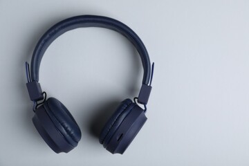 Pair of stylish blue headphones on light grey background, top view. Space for text