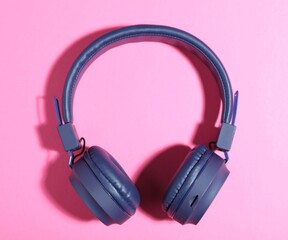 Pair of stylish blue headphones on pink background, top view