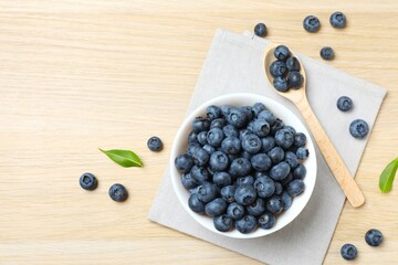 Top view of bowl with fresh tasty blueberries on wooden table, close up