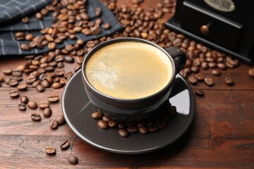 Aromatic coffee in cup, beans and grinder on wooden table, closeup