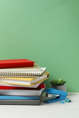 Stack of different books and notebooks on white table