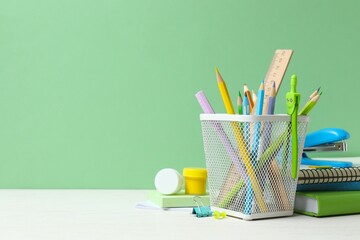 Obraz premium Colorful and modern workspace with pencil holder, notebooks and green wall