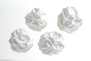 Four crumpled white paper balls isolated on white background showing texture and shadows