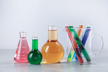 Different laboratory glassware with color liquids on light background