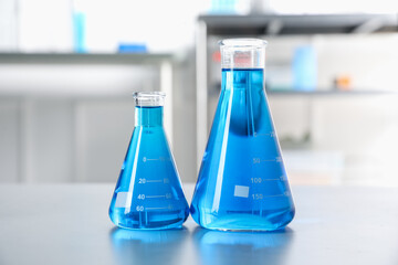 Flasks with light blue liquid on table in laboratory