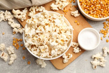 Tasty popcorn and corn kernels on light grey table, flat lay