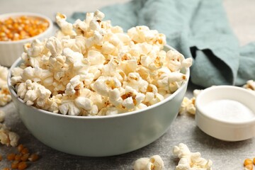 Tasty popcorn and corn kernels on light grey table, closeup