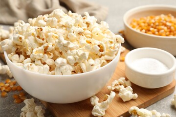 Tasty popcorn and corn kernels on light grey table, closeup