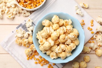 Tasty popcorn and corn kernels on light wooden table, flat lay