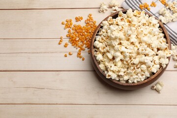 Tasty popcorn and corn kernels on light wooden table, flat lay. Space for text