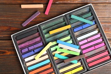Set of colorful chalk pastels on wooden table, flat lay