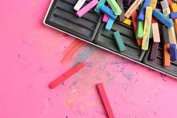 Many colorful chalk pastels on pink background, flat lay