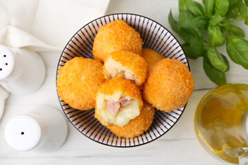 Delicious fried croquette balls in bowl and spices on white wooden table, flat lay