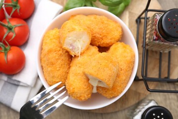 Delicious fried croquettes in bowl, tomatoes and spices on table, flat lay