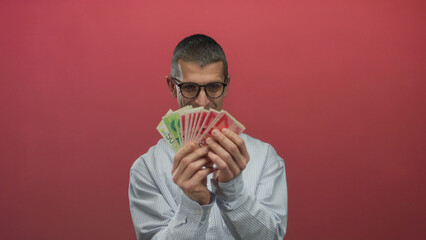 Man holding israeli shekels against a red background, focusing on money and financial concepts in...