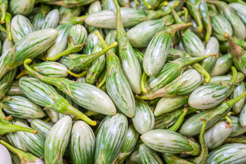 Generated imageFresh Thai eggplants shaped like a champak flower with green calyx stacked at a market stall, creating a colorful natural pattern ideal for background, texture, and healthy food concept