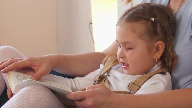 Tender reading scene with a mother and her child under the covers. Early education and nurturing interaction in a home setting. Close up.