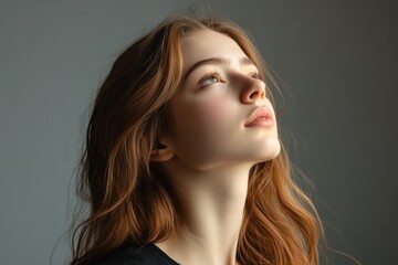 Naklejka premium Elegant young woman gazing thoughtfully against gray