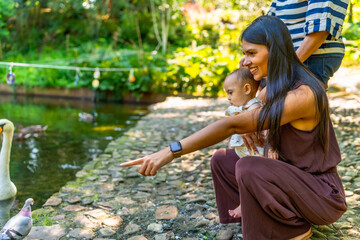 Latin family pointing at birds by the pond in botanical garden