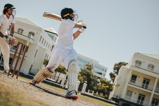 Male cricket batsman in action during a sunny outdoor match - Powered by Adobe