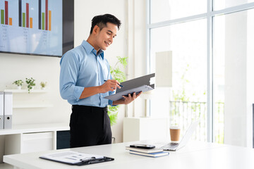 Asian businessman accountant analyst holding documents doing trade market research thinking working at office desk.