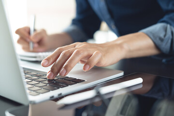 Closeup, business woman's hands working and typing on laptop computer keyboard on office table....